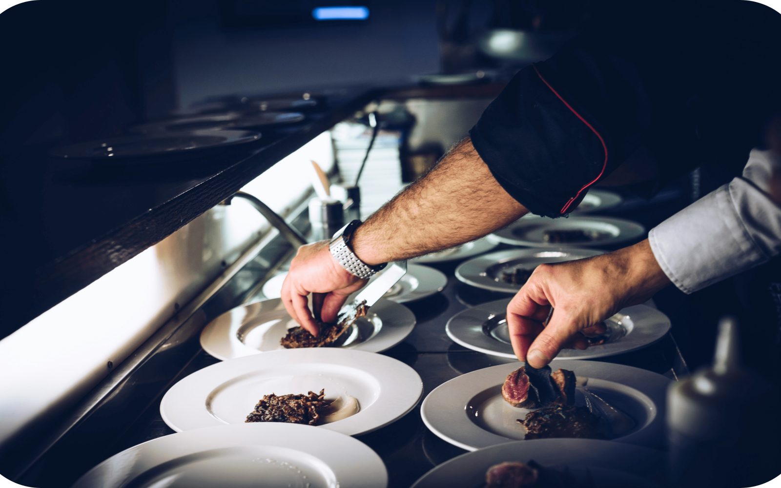 A chef plating dishes at the pass